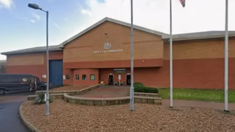A Google streetview image of HMP Doncaster. A brick built building with high walls. A sign above the door says HMP & YOI Doncaster. 