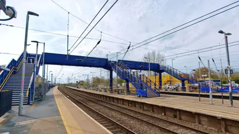 Network Rail A close up of the new, blue footbridge at Harlington station, with the overhead cables passing underneath it. The new structure is designed to last 120 years. 