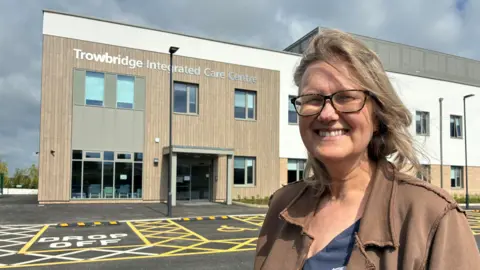 Councillor Mel Jacob smiles while standing in front of the new Trowbridge Integrated Care Centre building.