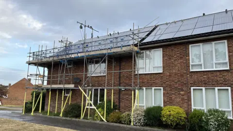 Darren Rozier/BBC A building that is used as sheltered housing. There is some scaffolding around one end the building which birds sit on. There are also solar panels installed on the roof of the building.