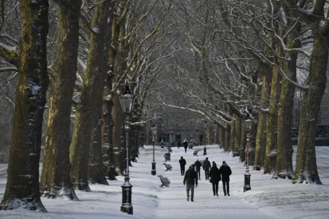 EPA People walk through Green Park after a snow flurry in central London