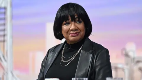 Diane Abbott is wearing a black leather jacket.