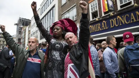 Getty Images People in London hold their fist in the air during a vigil for hate crime victims