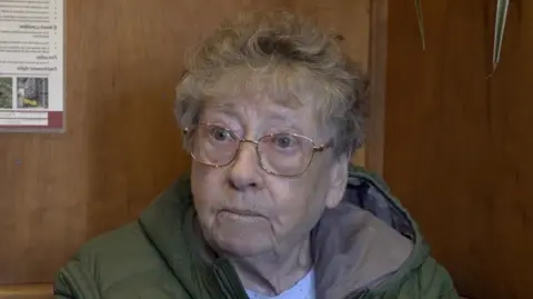 LDRS An elderly woman with rose gold-frame glasses.