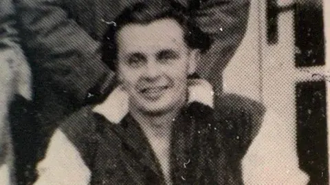 Harwell Campus A close up of a black and white photo of Griff Bowen in his early 20s, from a football team photo in 1948. Griff has straight black hair slicked back and wears a large black and white football shirt.