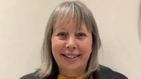 Carol Hyatt smiling. She has grey hair that is styled into a bob with a fringe