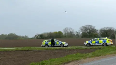 Jenny Kirk/BBC Police cars on a road near an abattoir