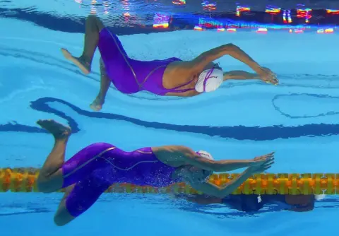 Reuters A swimmer in a purple costume is seen underwater. An unusual reflection makes it look like there are two of her.