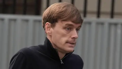 Brian Lawless/PA Wire James Lawrence arrives at the High Court in Dublin. He has short blond hair and wears a black top with a zippered collar.