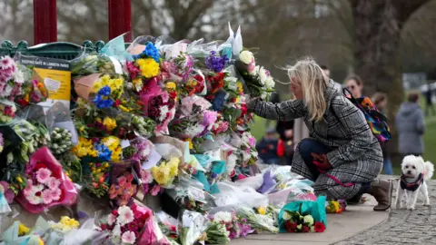 PA Media People leave floral tributes at the band stand in Clapham Common after the murder of Sarah Everard.