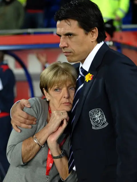 Getty Images Carol is comforted by Wales manager Chris Coleman at a 2012 international memorial game for her son