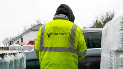 A person in a yellow high-vis coat on. It says South East Water on the back.