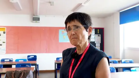 Cynthia Hollinsworth looking to the left wearing a black top and a red lanyard.