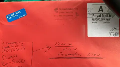 Letter sent mistakenly to Penarth, south Wales rather than Penrith, Australia. It is a red envelope with writing in biro with the air mail sticker and stamp visible in the top left and top right 