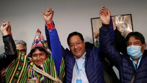 Reuters Presidential candidate Luis Arce of the Movement to Socialism party (MAS) reacts next to vice presidential candidate David Choquehuanca, who wears a protective face mask, after addressing the media during the presidential election in La Paz, Bolivia, October 19, 2020.