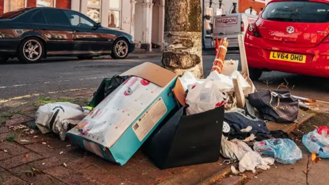 @khandiephoto A pile of boxes and bags full of rubbish on the pavement of a Northampton street