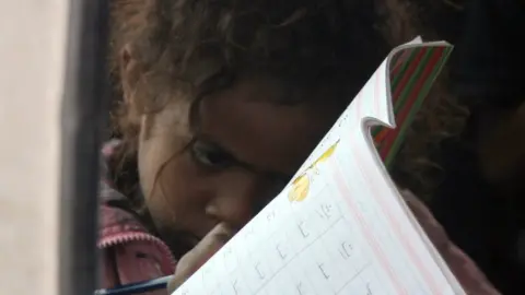 MOHAMMED HUWAIS / AFP A Yemeni young girl writes in an exercise book inside a minibus turned into a mobile classroom in Sanaa