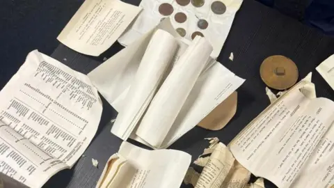 A selection of papers, coins and documents, laid out on a table