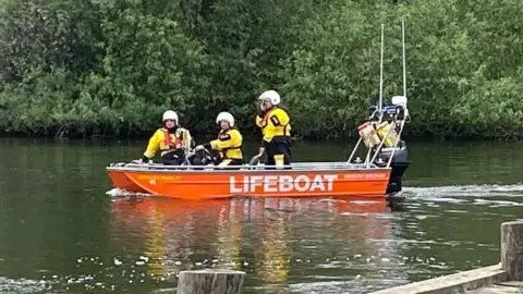 Mariam Issimdar/BBC An orange lifeboat launched in the water with three personnel on board.