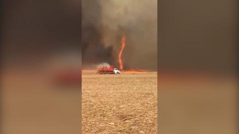 Firenado in distance with red truck in foreground