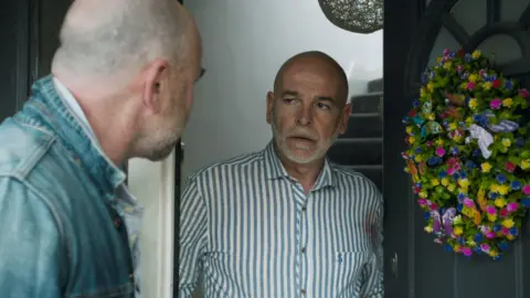 Corrie character Richie Parkinson (Nathan Sussex) opens the front door. He has blood on his shirt