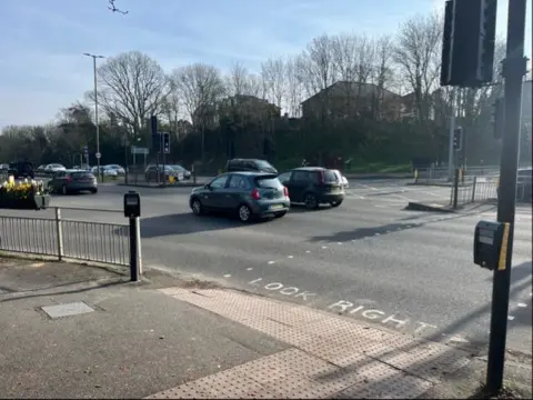 Roadside railings with two bunches of yellow memorial flowers attached.
