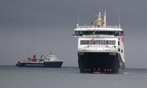 PA Media A small black and white ferry and a much larger newer ship, pictured heading towards the camera.