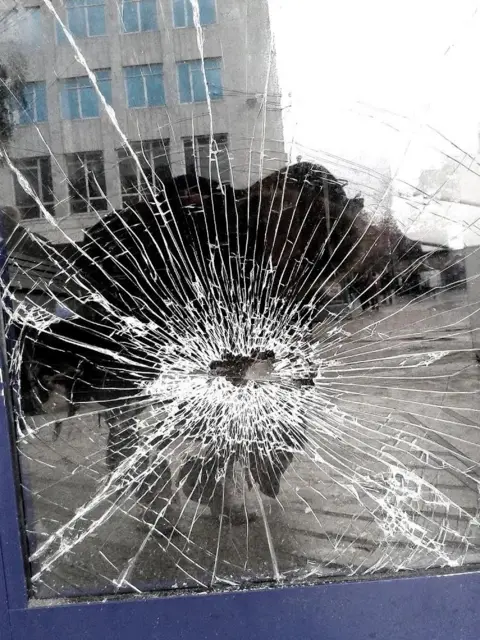 Jojo Arnell A reflection of a photographer taking a picture of broken glass in a door window.