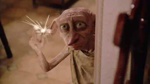 Alamy/Warner Bros A computer-generated image of Dobby. He is a small creature, with a face similar to a human's but with pink skin, large green eyes, long pointy ears and a long pointy nose. He is wearing a light brown coloured sack for clothes.