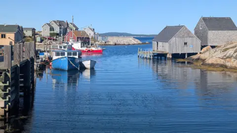 Supplied by Kent Truscott An image showing small grey houses and rocky terrain on the Atlantic in Nova Scotia, along with two small boats, one blue and one red.