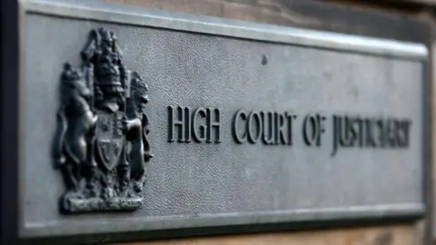 PA Media A grey sign at the High Court in Edinburgh which reads 'High Court of Justiciary'.