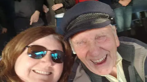 Family Handout Smiling woman in shades next to man in fisherman's hat.