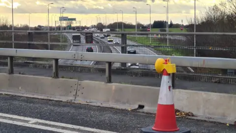 Stuart Woodward/BBC A cone and barrier on the bridge, with vehicles on the A12 being driven in the background.