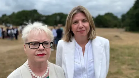 Helen Lowe, the school's former headteacher, and her successor Sharon Maher attended the memorial event on Wimbledon Common. Other attendees can be seen standing behind them.
