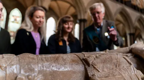 Salisbury Cathedral A tour guide shows visitors the graffiti on an historic tomb with the use of a torch.
