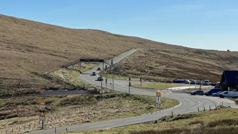 BBC The Mountain Road at the Bungalow with the road snaking into the distance under a metal footbridge.
