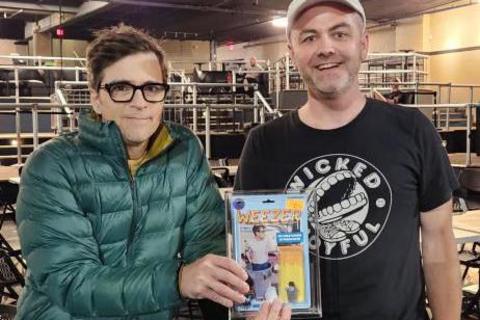 Nick Lavellee (right) handing an action figure he created to Weezer frontman Rivers Cuomo.