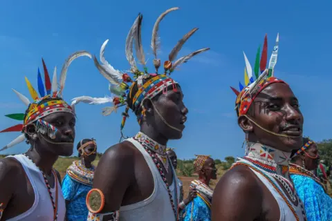 GERALD ANDERSON / GETTY IMAGES Three men from the Rendille community wear colorful beaded jewelry and feather headdresses. 