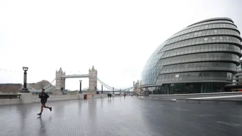 PA Media City Hall on the right of the picture and Tower Bridge on the left with a jogger in the foreground. 