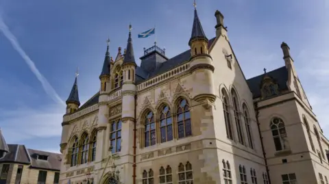 Getty Images Built to a Flemish-Baronial style, Inverness Town House is a sandstone building with turrets and ornately designed windows. A Saltire flag flutters from a pole on the roof.