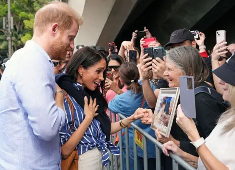 Getty Images Harry and Meghan react emotionally to a fan showing them a framed picture.
