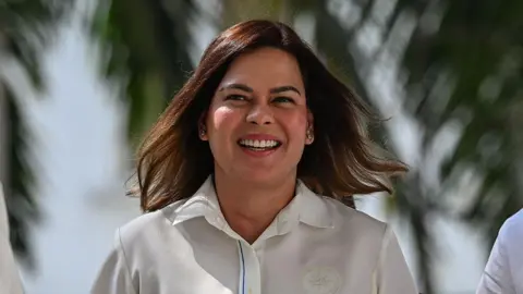 Sara Duterte walking and smiling with the wind blowing her hair