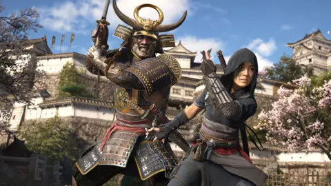 Ubisoft Screenshot shows 2  characters successful  the plot  of a achromatic  Japanese castle arsenic  some  follow  conflict  stances. One is simply a hulking warrior successful  bulky samurai armour and a horned aureate  helmet, holding a katana precocious   and acceptable   to strike. In beforehand   of him, a pistillate  ninja holds a throwing prima  successful  each   hand, acceptable   to motorboat  them.