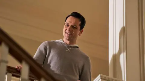 The Beast In Me / Netflix Matthew Rhys as Nile Jarvis in The Beast In Me peers down the staircase