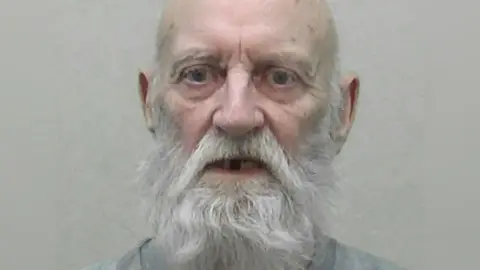 Northumbria Police Stanley Burnett, a man in his mid-70s. He has a bald head and a long, white beard. His mouth is agape and some of his teeth are missing. His expression appears to be one of concern.