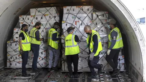 Getty Images Workers unload flowers from a plane at Miami International Airport on February 08, 2022