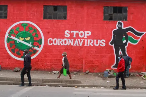 SOPA Images Kenyans walk past an informative mural about the Coronavirus along Haile Selassie avenue in Nairobi.