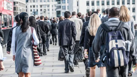 Commuters walking along a pavement in a city