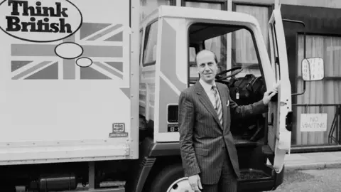 Getty Images Norman Tebbit in front of a lorry with a Think British slogan