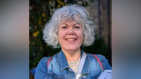 Maxine Webb Maxine Webb is smiling while wearing a denim jacket on top of a cream top.